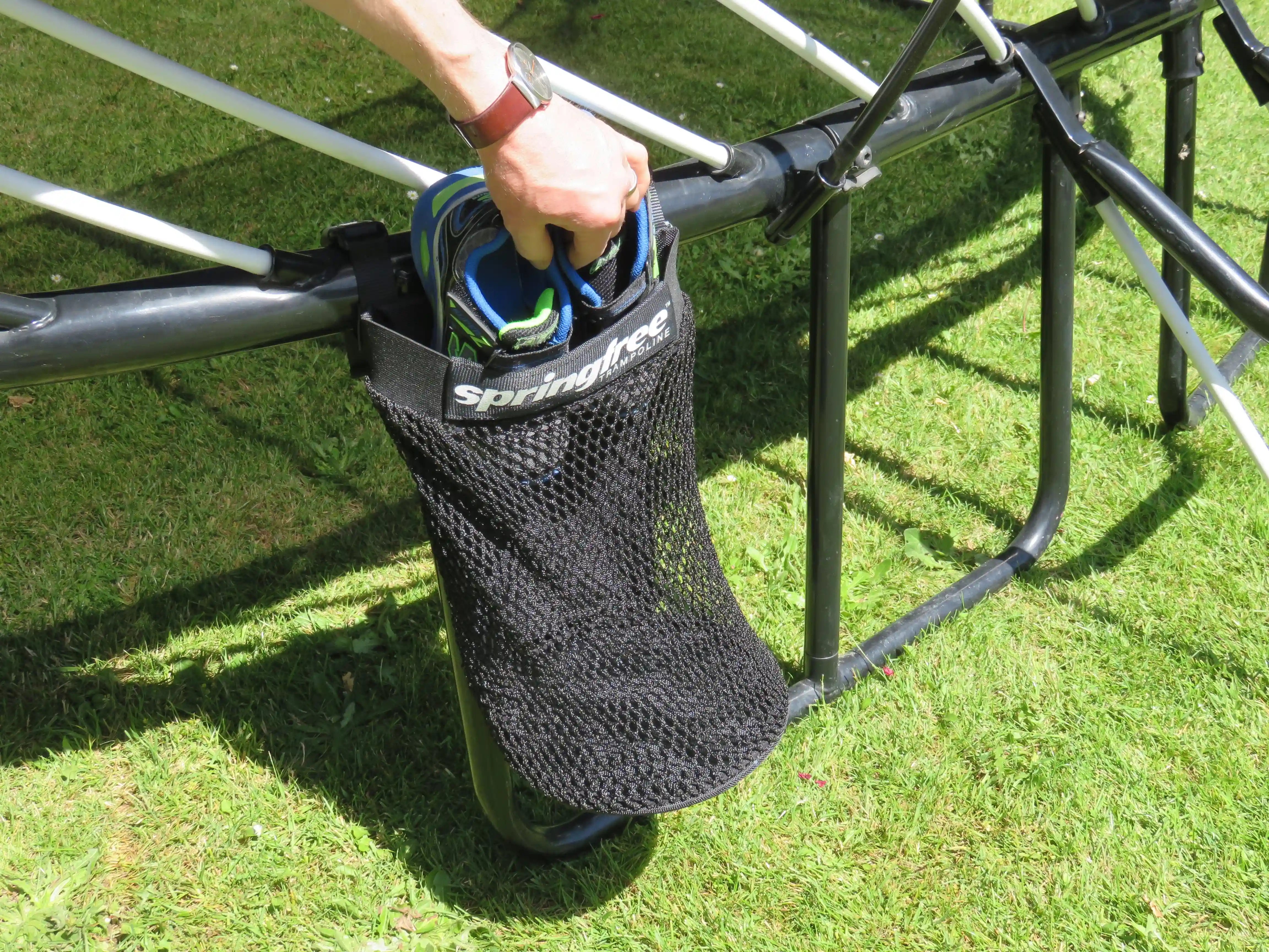 placing shoes inside a storage bag attached to a trampoline