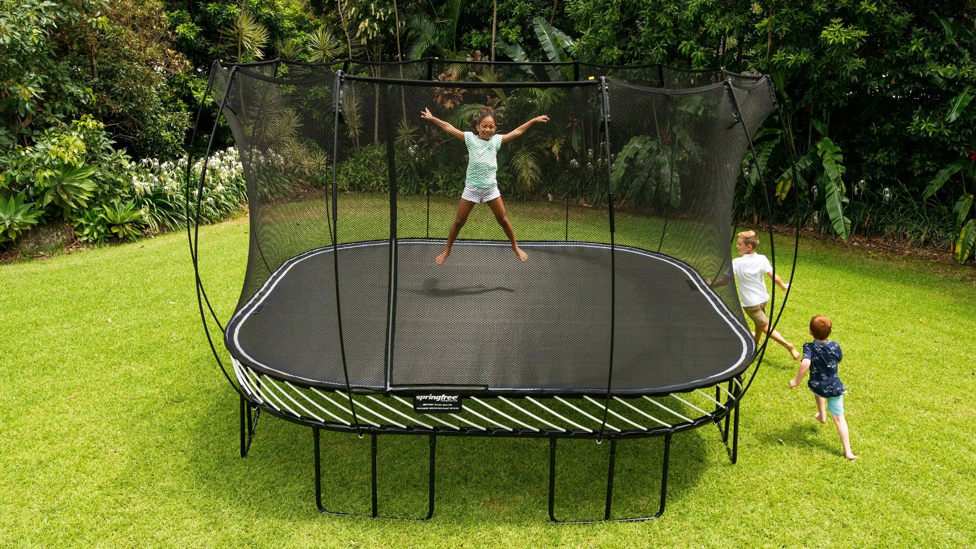 girl jumping on a trampoline while kids are playing around