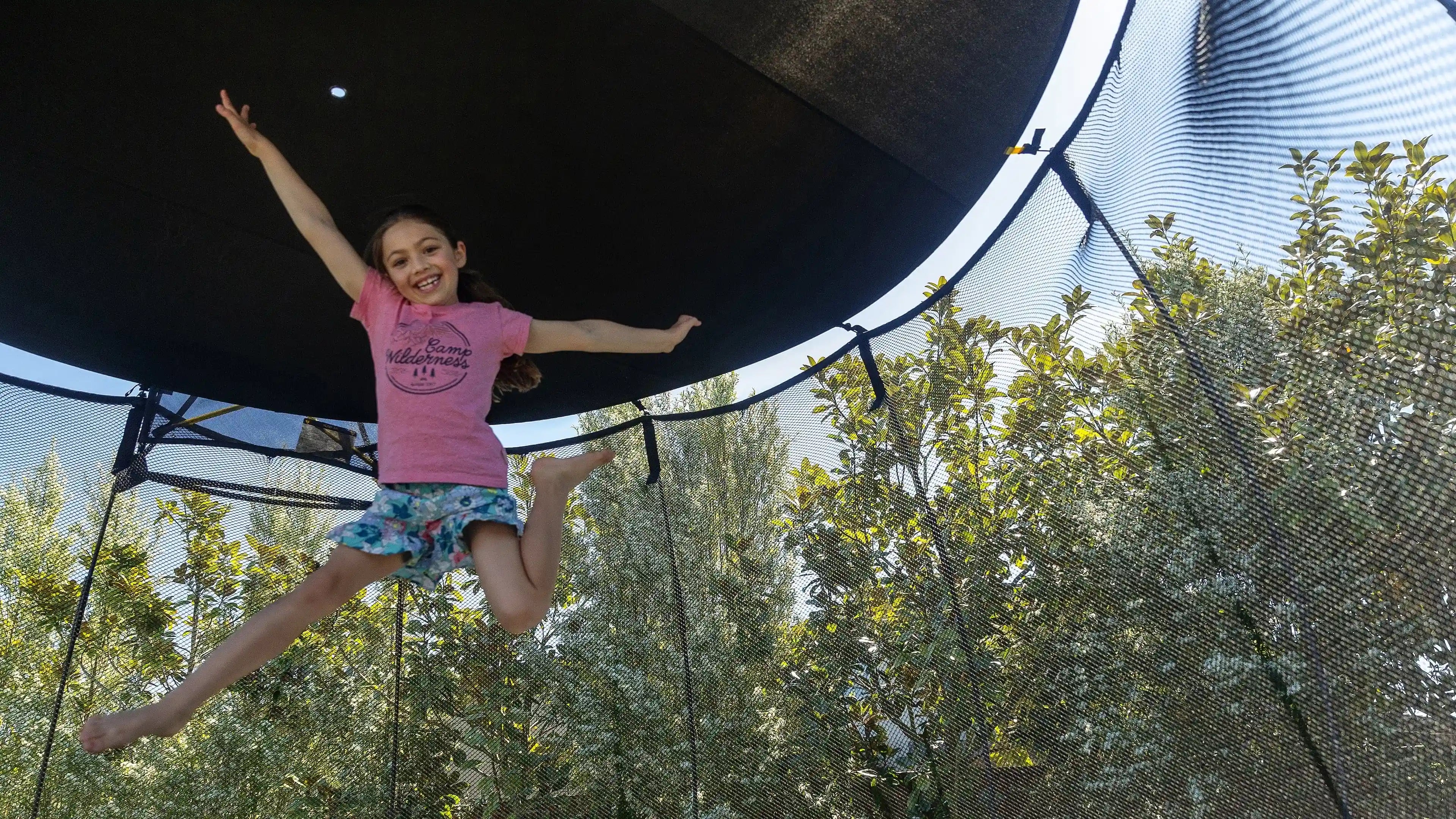 girl jumping on a trampoline with a sun shade