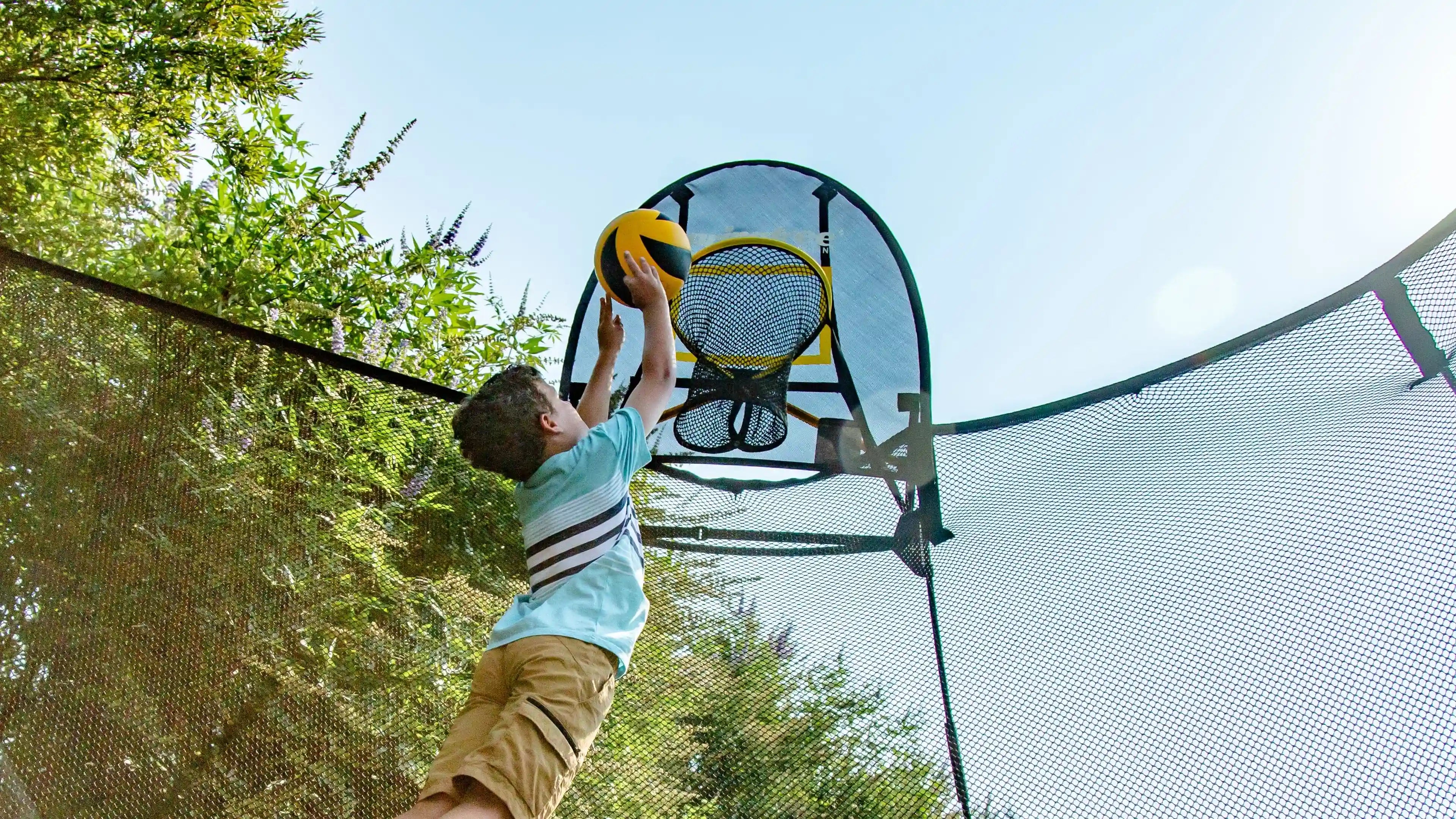 boy dunking the ball on the hoop attached to a trampoline